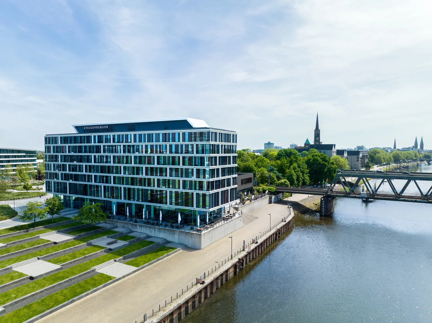 Modern waterfront hotel shown from above with bridge and river view Drone view of a modern hotel by the water with river, bridge and city
