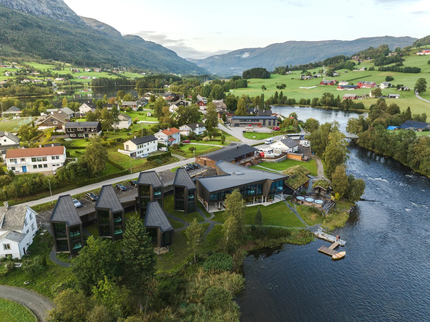 Aerial perspective on a hotel in a scenic natural location Drone view of a modern hotel in a natural riverside setting with surrounding landscape and mountains