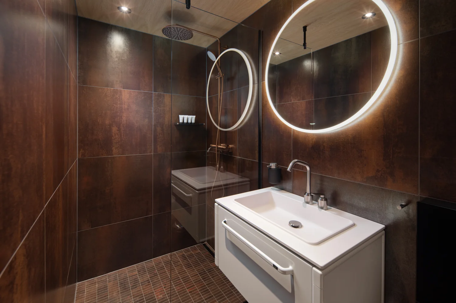 Modern hotel bathroom with clean lines and balanced light Modern hotel bathroom with rain shower, refined design and illuminated mirror