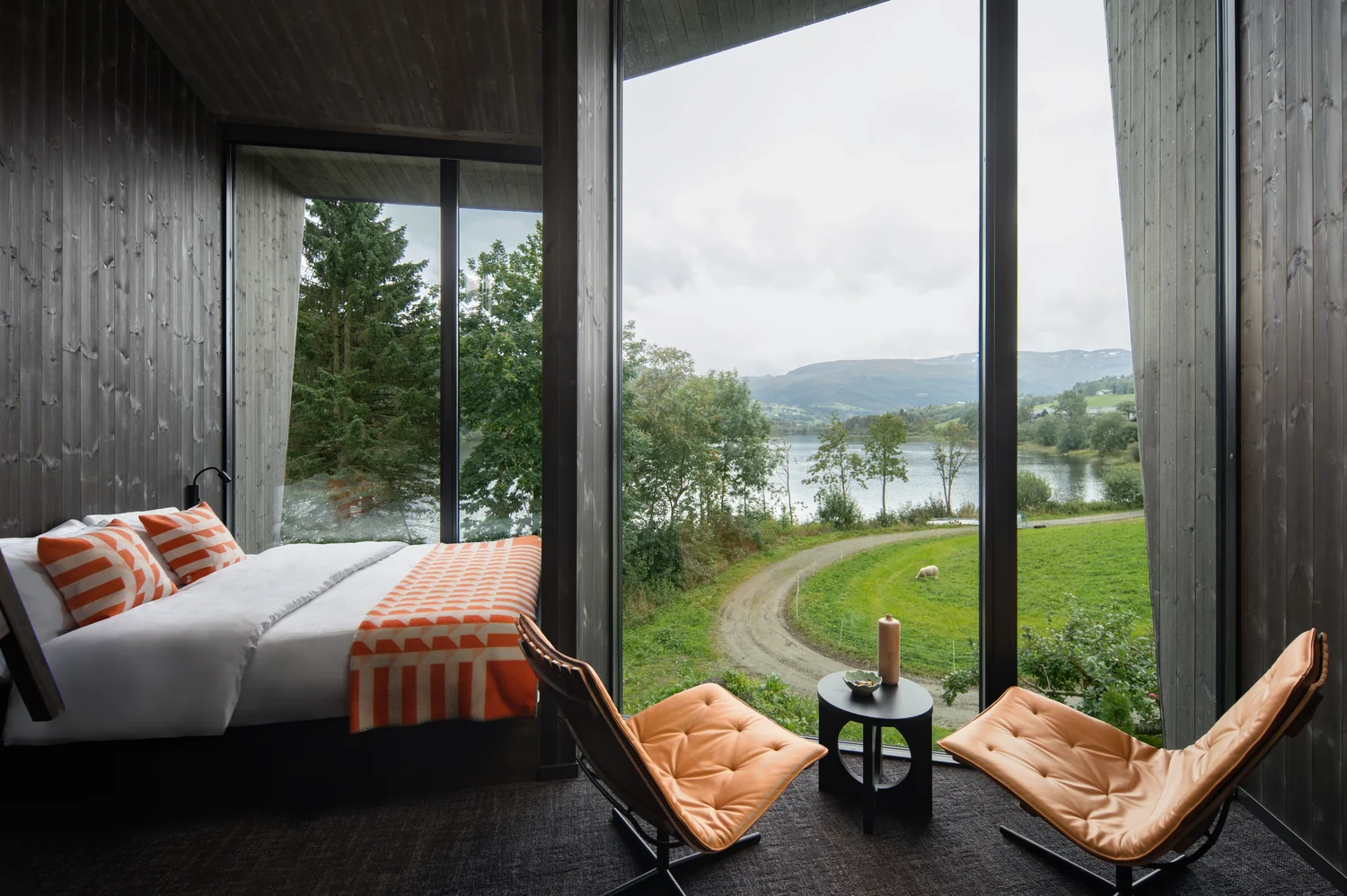 Hotel room with panoramic view and a calm, inviting mood Modern hotel room with panoramic window, seating area and view of nature and lake