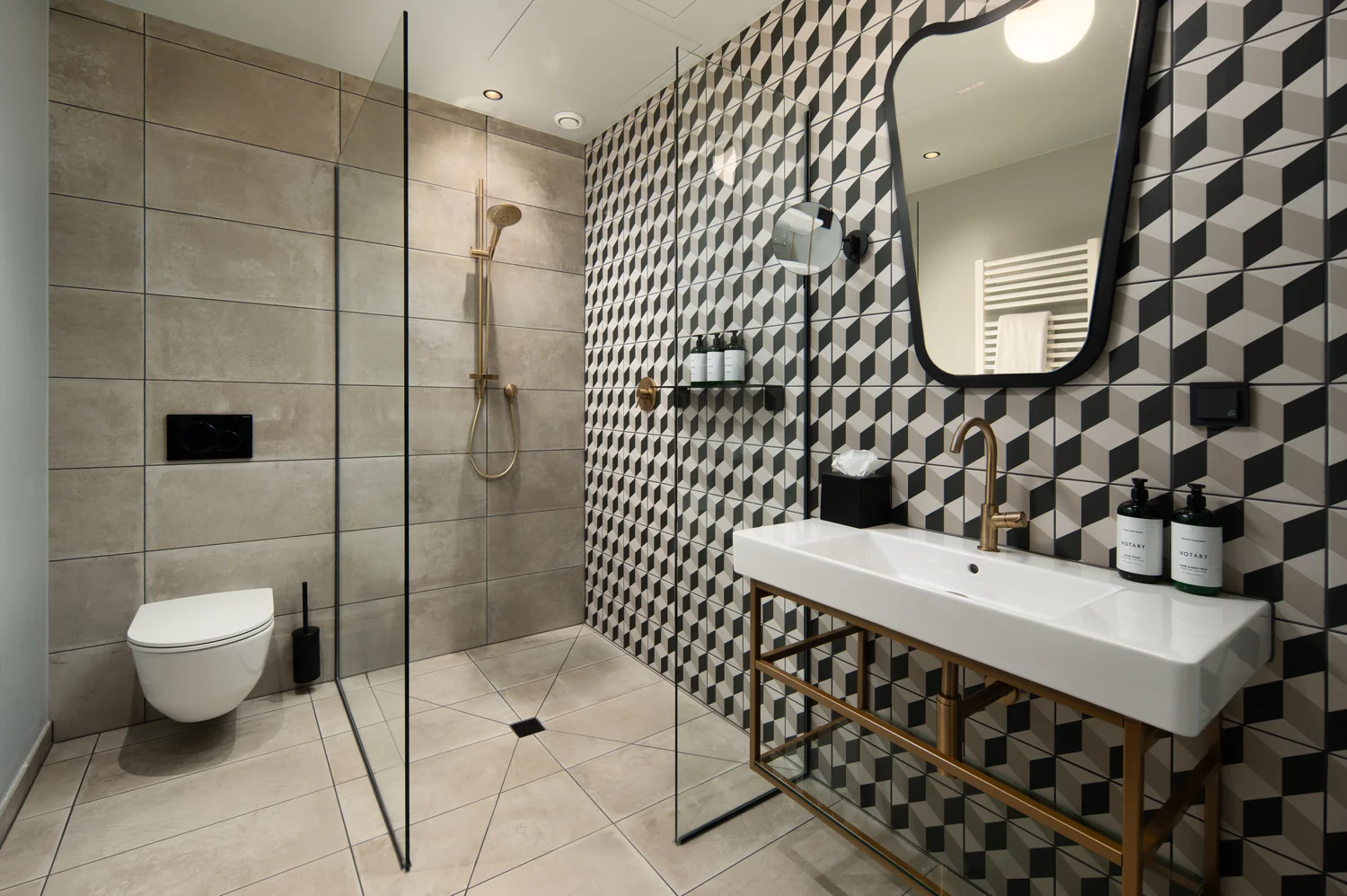 Design-focused hotel bathroom with graphic surfaces and precise composition Design-oriented hotel bathroom with walk-in shower, graphic tiles and premium fittings